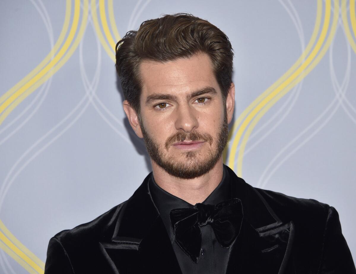 A bearded Andrew Garfield in a black tux at a red-carpet event.