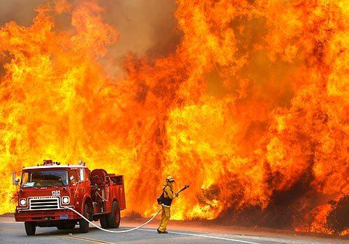 A firefighter from the California Department of Forestry and Fire Protection is dwarfed by flames along East Grade Road on Palomar Mountain. Authorities estimate that about 525,000 were ordered or urged to leave their San Diego County homes as the fires raged in October.