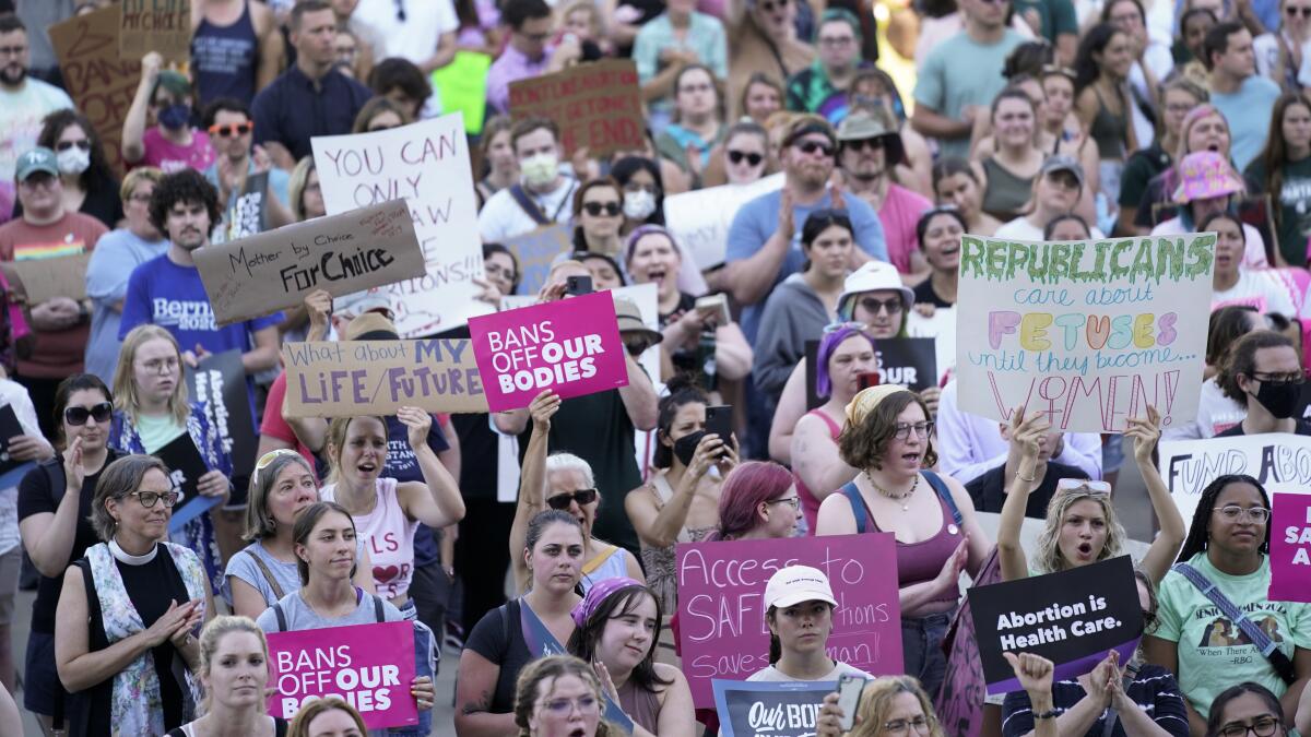 Abortion rights protesters hold signs at a rally outside the state Capitol.