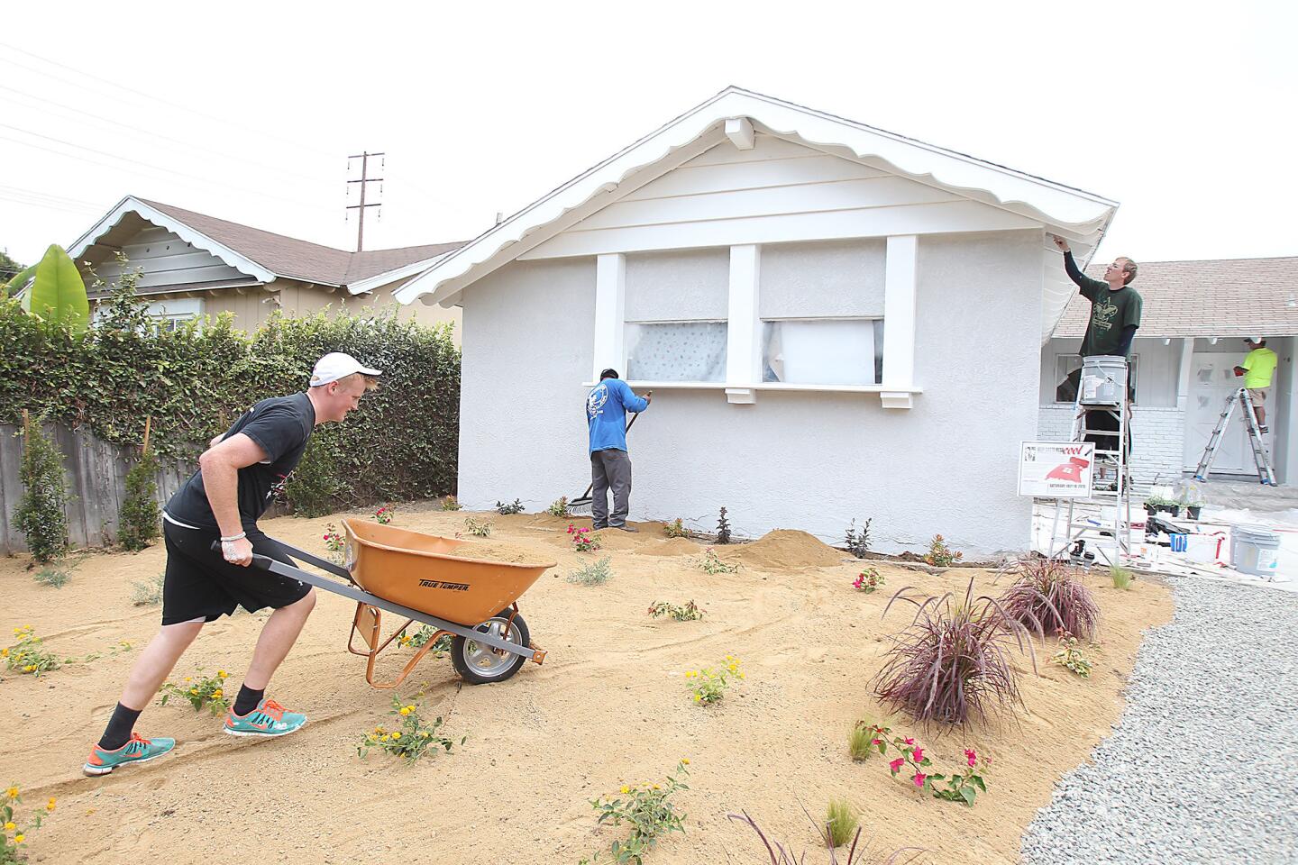 Volunteer John Gough hauls a load of dirt material to the front yard of a home on Raleigh Ave. during Neighbors Helping Neighbors charity event in Costa Mesa on Saturday. The program, organized by Mayor Steve Mensinger, uses private donations and volunteer labor from nine congregations from The Church of Jesus Christ of Latter-day Saints in Newport Beach and Costa Mesa to paint and fix up the homes.