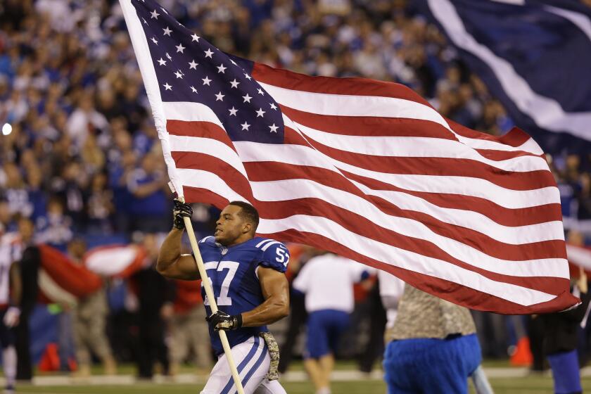 Indianapolis Colts linebacker Josh McNary carries the American flag before a game against the New England Patriots on Nov. 16.