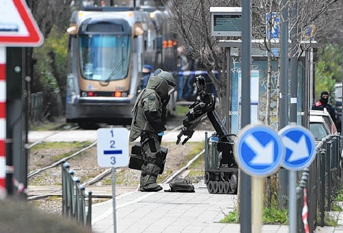 A bomb squad agent and robot stand near a suspicious package in Brussels.