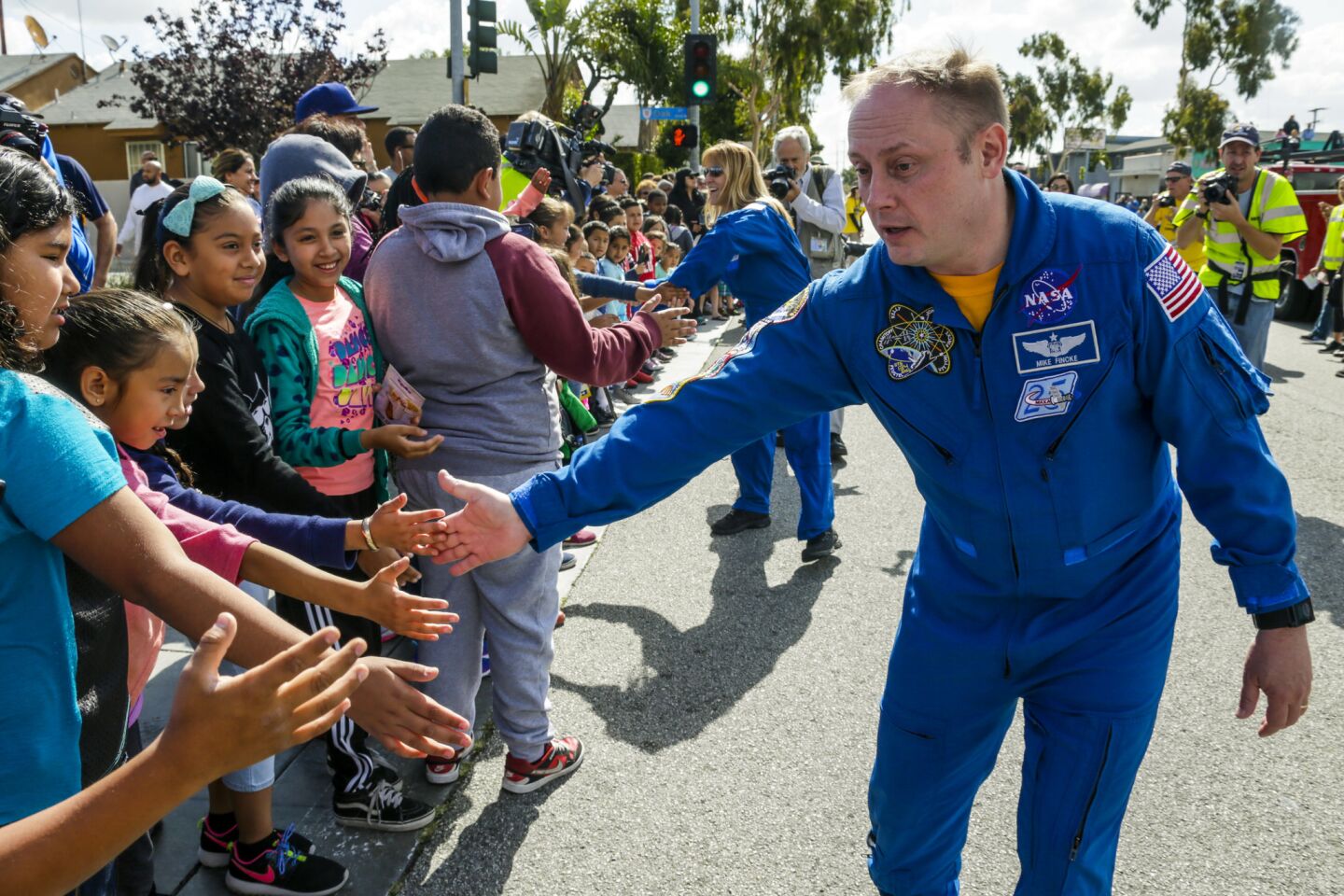 Astronaut Mike Fincke shakes hands with students from Oak Tree Elementary school standing along Arbor Vitae Street to witness ET-94, NASA's last remaining space shuttle external tank.