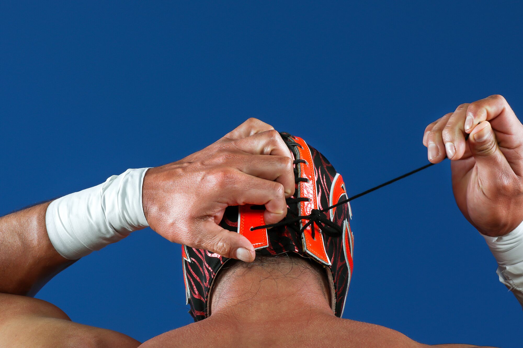 Rear view of a man lacing his lucha libre wrestling mask.