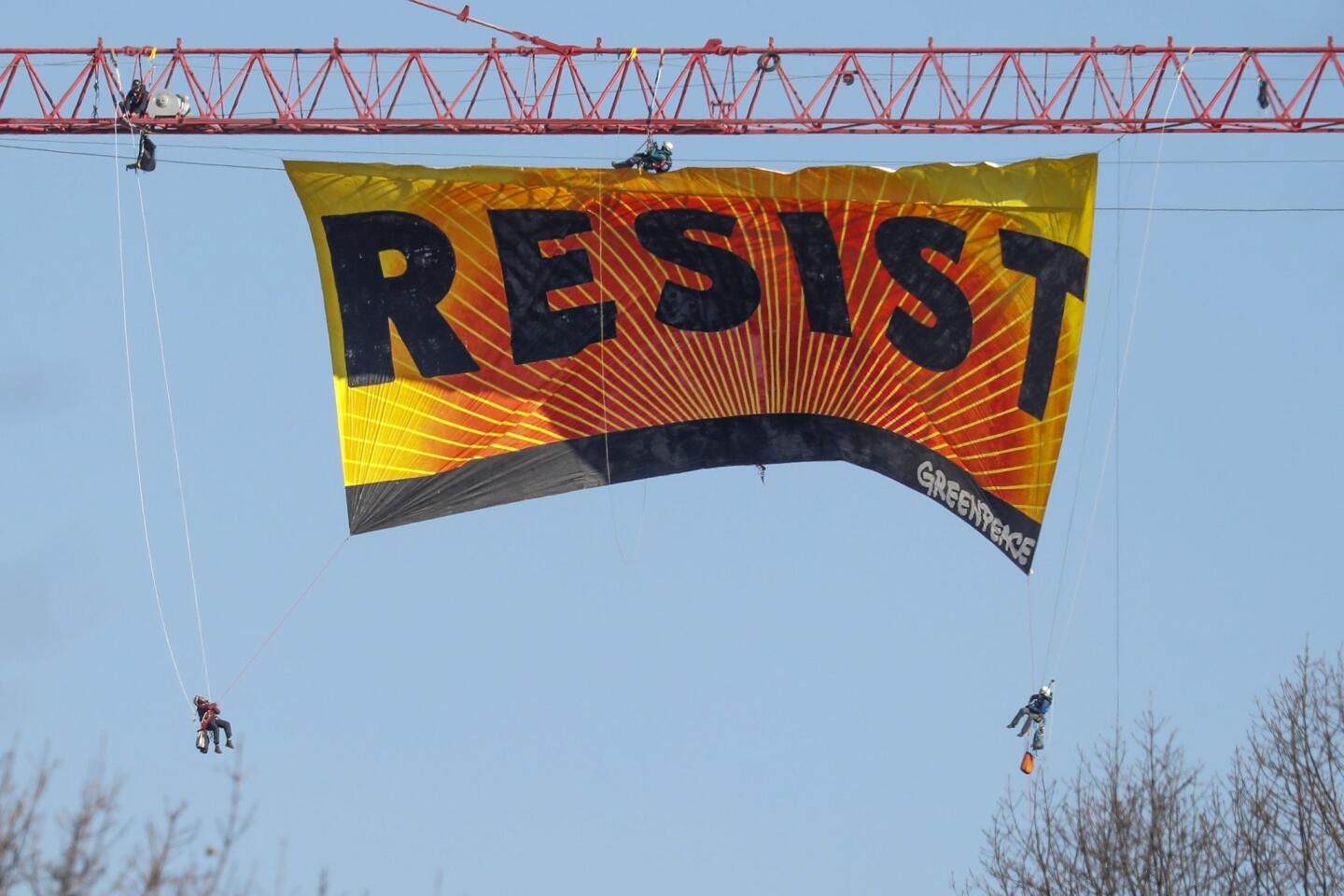 Siete activistas de Greenpeace extienden una enorme manta con la palabra 'RESIST' (Resistir) desde una grúa, cerca de la Casa Blanca en Washington DC.