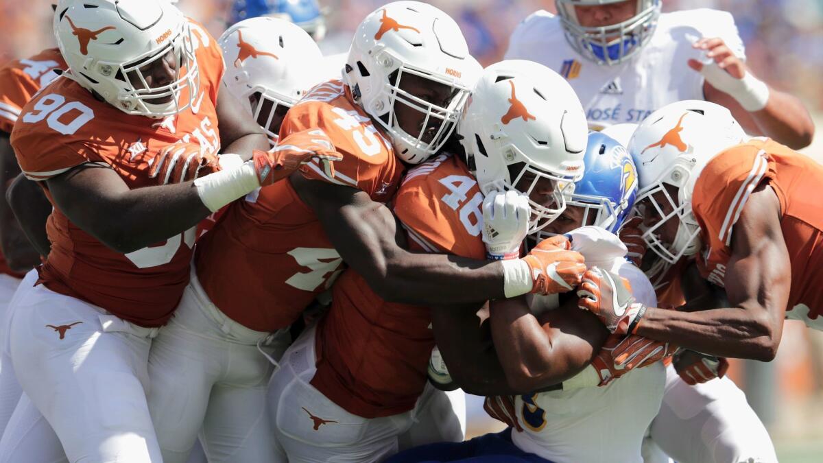 Texas' Malik Jefferson (46) and DeShon Elliott, right, help take down San Jose State's Tyler Nevens on Sept. 9.