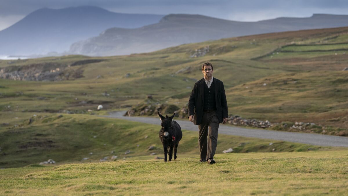 A man walks on a hilly Irish road with his miniature donkey in "The Banshees of Inisherin."