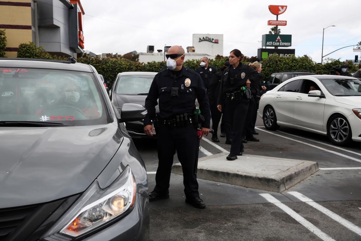 Los Angeles police officers wear masks while responding to a call in Crenshaw on Sunday.