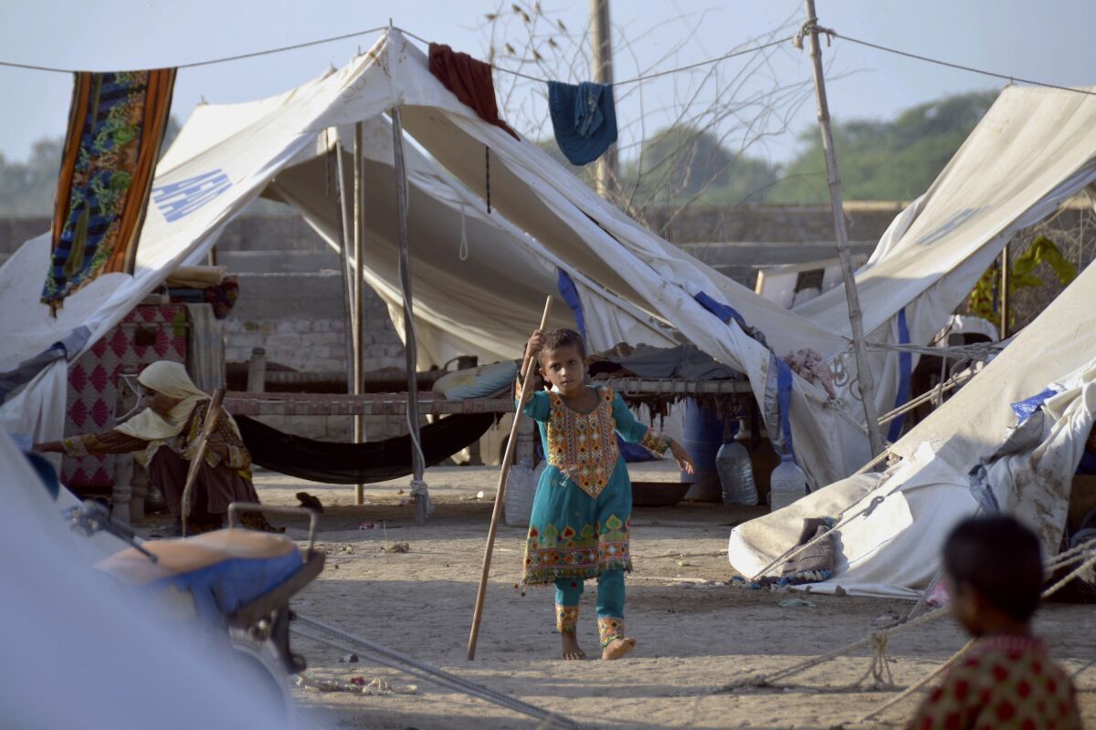 A young girl plays outside her tent at a relief camp, in Jaffarabad, a district in the southwestern Baluchistan province, Pakistan, Thursday, Sept. 29, 2022. Almost 3 million children in Pakistan may miss at least one semester because of flood damage to schools, officials said Thursday, following heavy monsoon rains likely worsened by climate change. (AP Photo/Zahid Hussain)