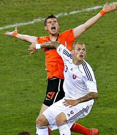 Slovakia defender Martin Skrtel, right, eyes the ball while trying to Netherlands striker Klaas-Jan Huntelaar at arm's length.