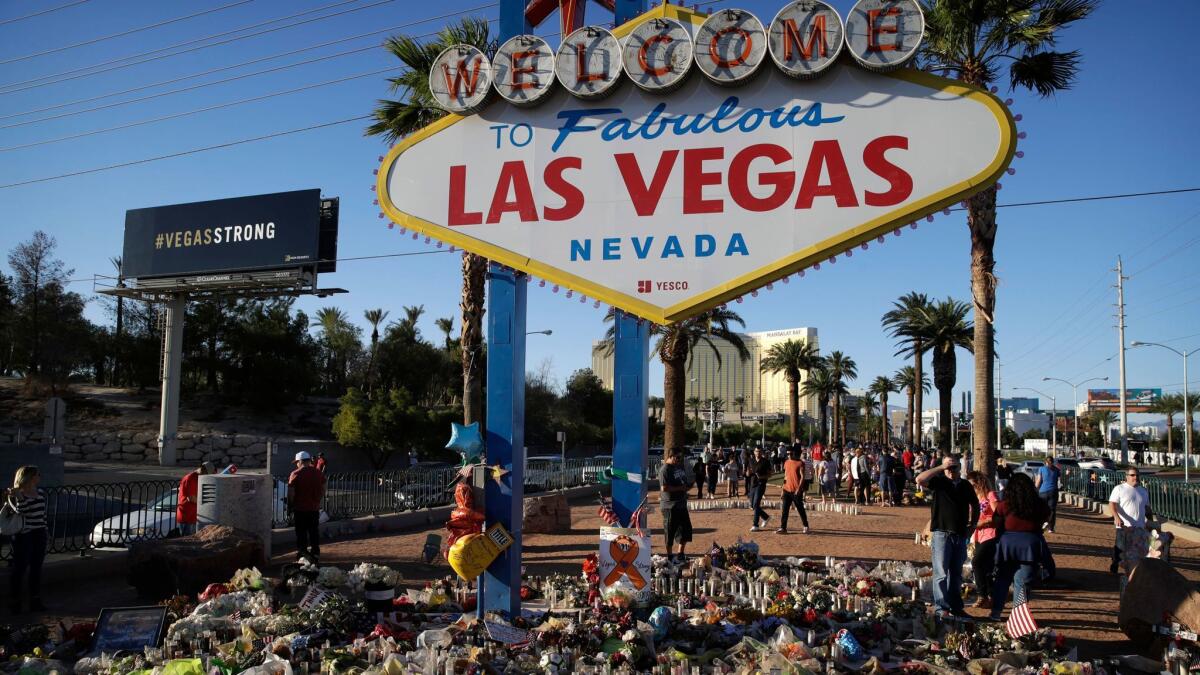Flowers, candles and other items surround the Las Vegas sign on Oct. 9 as a makeshift memorial for victims of a mass shooting earlier that month. The city has revived its famous slogan "What happens here, stays here."