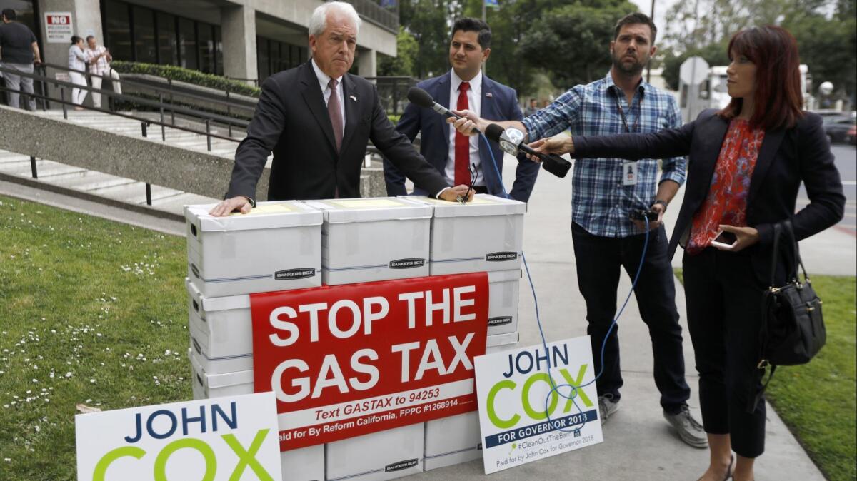 Gubernatorial candidate John Cox, left, and Bill Essayli, who is running for the 60th Assembly District, speak to the media in Norwalk on April 30 next to boxes filled with signatures for an initiative to repeal the gas tax.