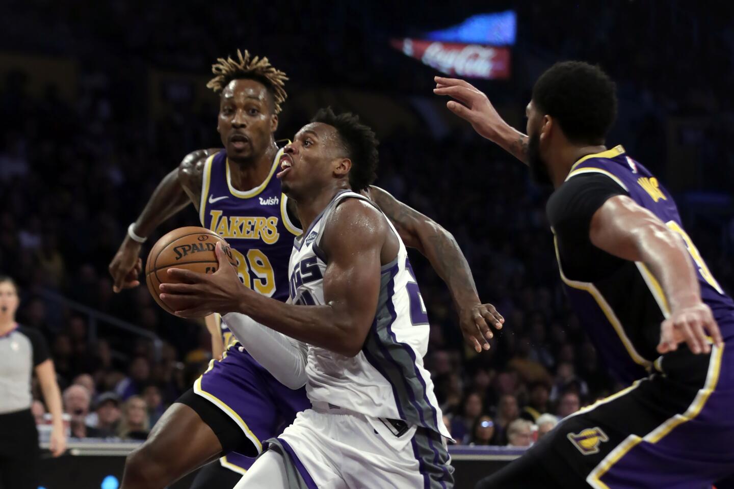Sacramento Kings guard Buddy Hield, center, drives to the basket between Lakers center Dwight Howard, left, and forward Anthony Davis.