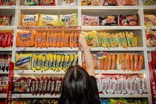 A worker sticks "highly recommended" labels in English and Chinese on the shelf of ramyon.