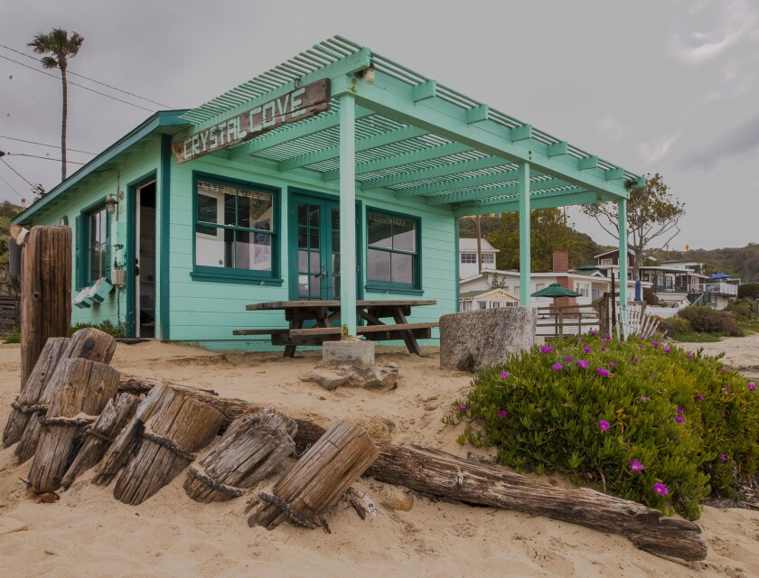 A green beach cottage with a sign that reads "Crystal Cove."
