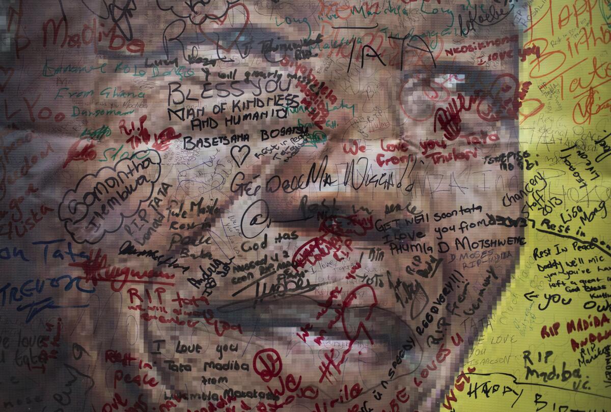 Messages written by mourners cover a poster of Nelson Mandela near his former home in the Soweto township of Johannesburg, South Africa.
