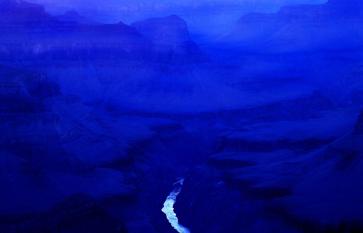 The Grand Canyon in deep purples and blues with a sliver of water at the bottom.