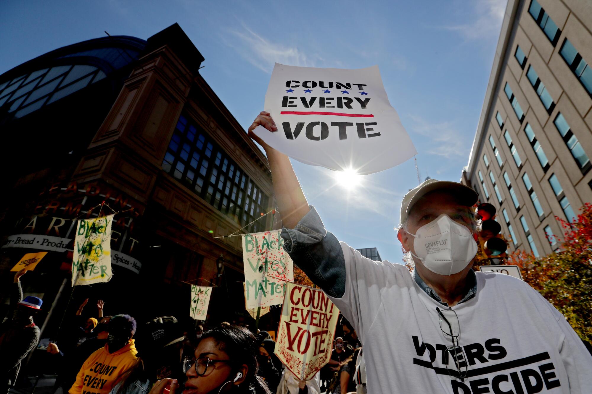People hold signs reading "Count every vote" and "Black votes matter."