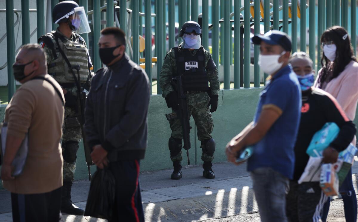 Members of the Mexican security forces, wearing face shields, stand guard as family members wait for news about their relatives near the General Hospital in Ecatepec, on the outskirts of Mexico City, on May 2, 2020.
