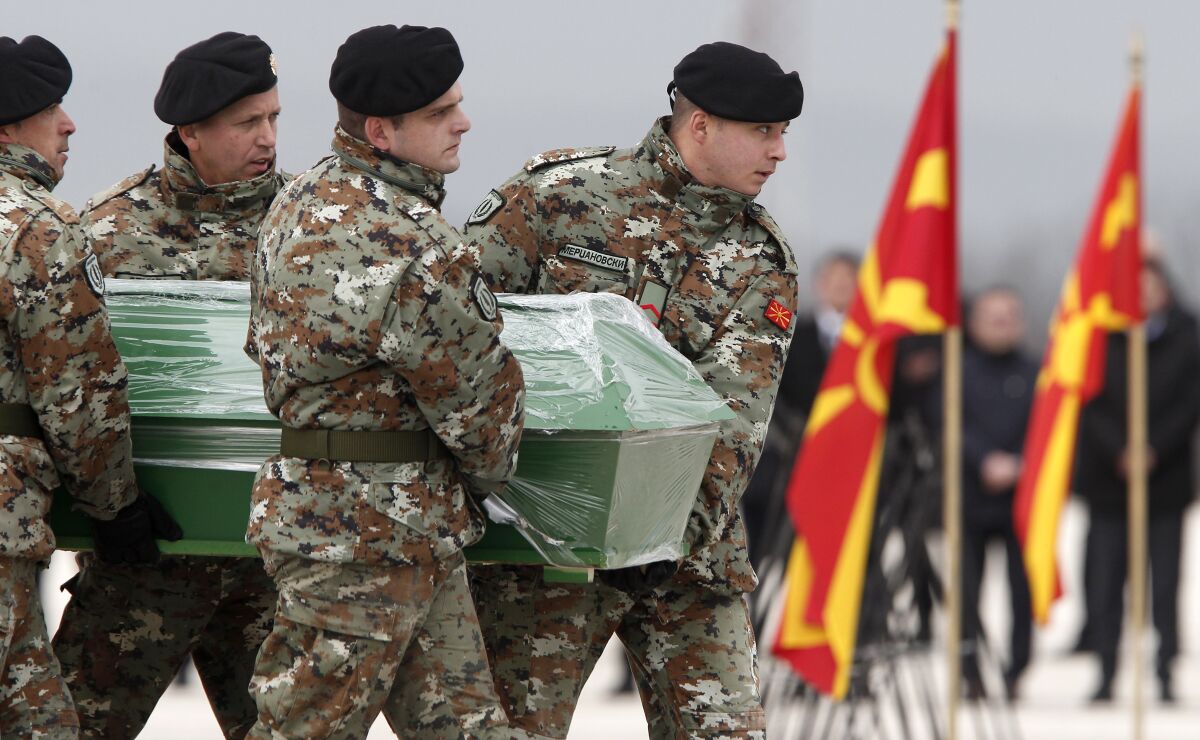 Army soldiers carry a coffin containing the remains of a passenger killed in a bus crash in Bulgaria ten days ago, during the repatriation ceremony at Skopje Airport, North Macedonia, Friday, Dec. 3, 2021. Two Bulgarian military planes have landed Friday at North Macedonia's main airport carrying remains of 45 people killed in bus crash in Bulgaria ten days ago to be handed to their families for burials. (AP Photo/Boris Grdanoski)