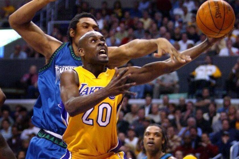 Gary Payton puts up a layup after driving past Timberwolves center Michael Olowokandi in March 2004 during Payton's only season with the Lakers.