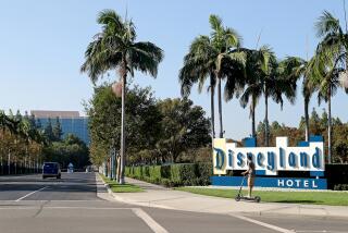 A scooter cruises by the Disneyland Hotel marquee along Magic Way in Anaheim.