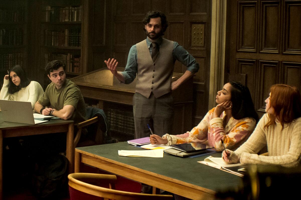 Penn Badgley stands in a lecture hall.