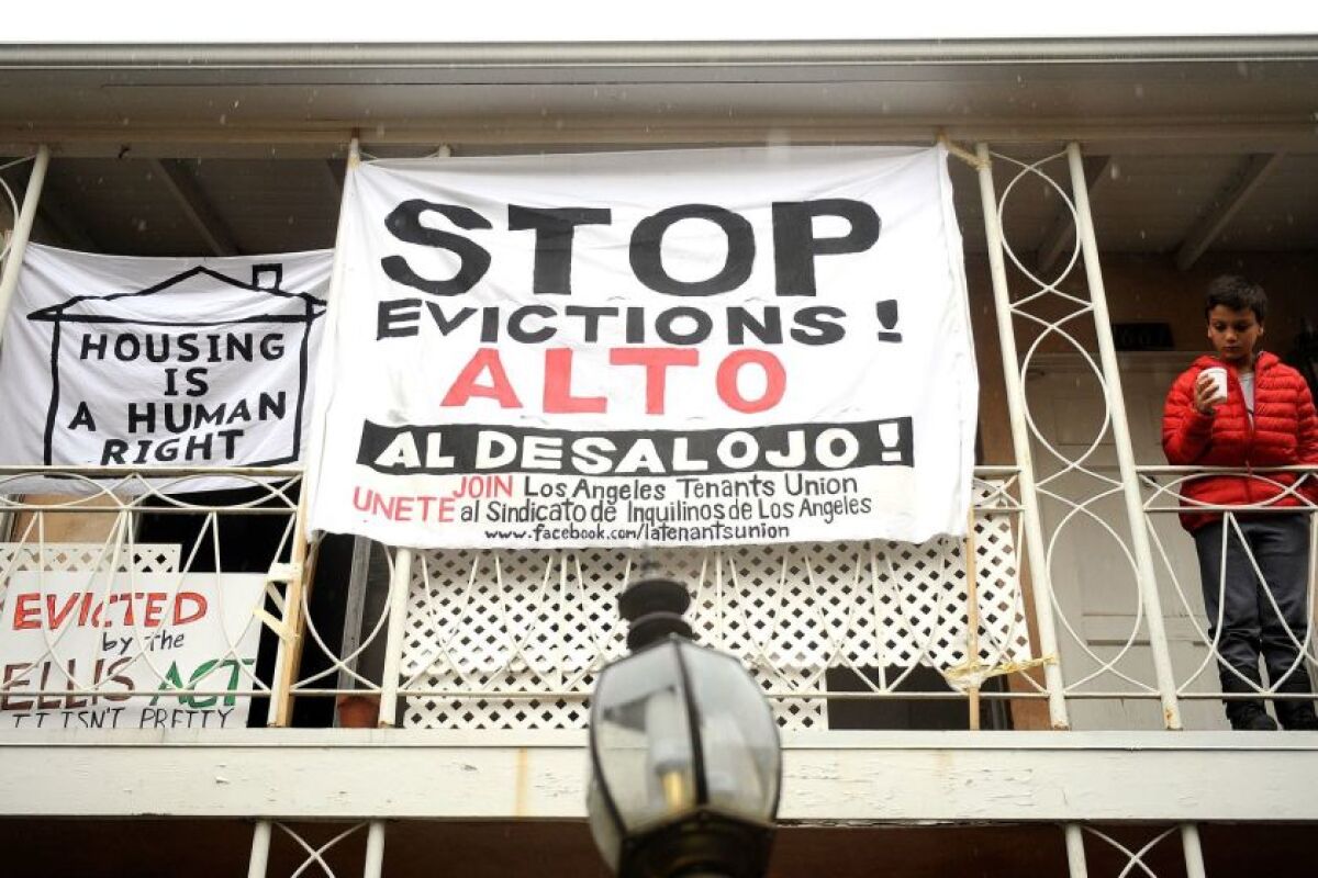 Signs outside apartments read "Stop evictions!" in English and Spanish, and "Housing Is a Human Right."