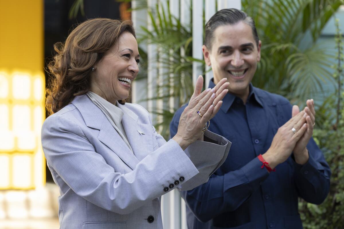 Vice President Kamala Harris and Frankie Miranda stand together and applaud. 