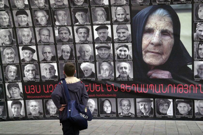 In this photo provided by the Photlure photo agency in Armenia, a boy pauses in front of a wall-sized poster depicting the faces of 90 survivors of the mass killings of Armenians in the Ottoman Empire, in Yerevan, Armenia, April 20, 2005. The composition was done to commemorate the 90th anniversary this Sunday April 24th of the beginning of what Armenians say was the killing of 1.5 million of their people as the Ottoman Turks forced them from eastern Turkey between 1915 and 1923 _ and that this was a deliberate campaign of genocide. (AP Photo/Herbert Bagdasaryan, HO) ORG XMIT: NY118
