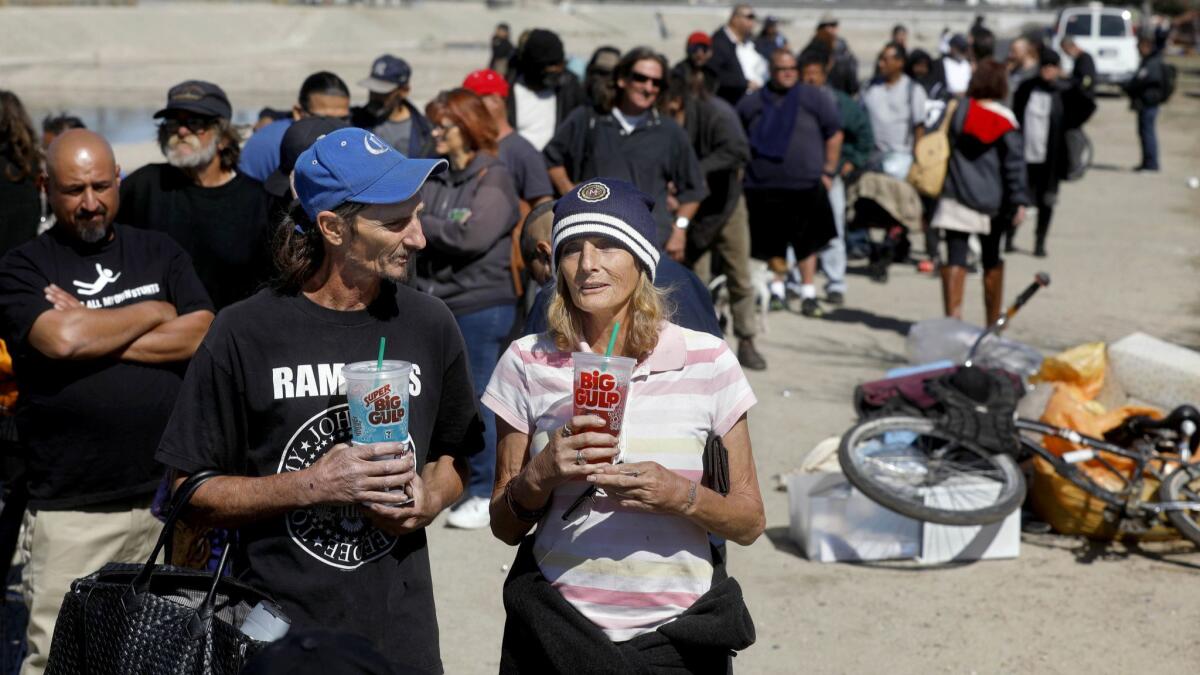Homeless people wait for motel vouchers after being evicted from a riverbed encampment in Anaheim last year. CalOptima plans to roll out a new program next month to medically treat homeless people on the street.