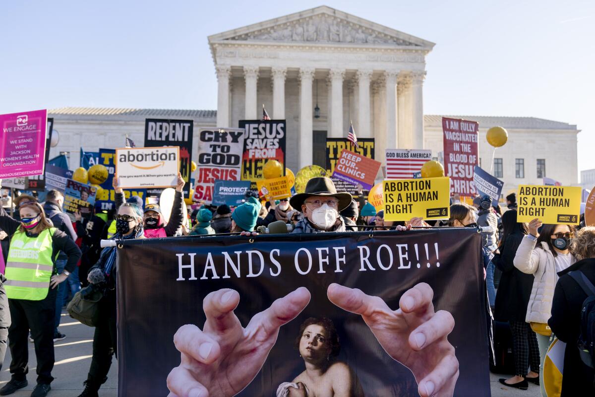A crowd of people with signs protesting outside the U.S. Supreme Court