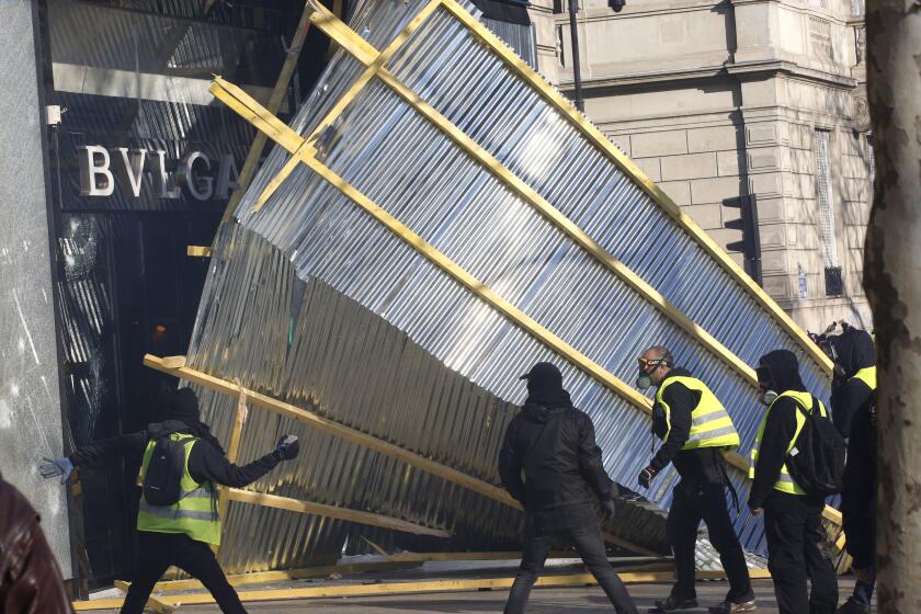 FILE - In this March 16, 2019 file photo, protesters remove a protective wall from a luxury shop during a yellow vests demonstration in Paris. A summer of incidents, from insults to attacks, some deadly, has built into a crescendo of violence. But has France really grown more “savage” as Interior Minister Gerald Darmanin says? Or is the problem a growing sense of insecurity fueled by the word “savage” itself, as Justice Minister Eric Dupond-Moretti contends? The verbal jousting is causing divisions, and worrying critics who say the interior minister is exploiting the language of the far right to help President Emmanuel Macron’s party win upcoming elections. (AP Photo/Christophe Ena, File)