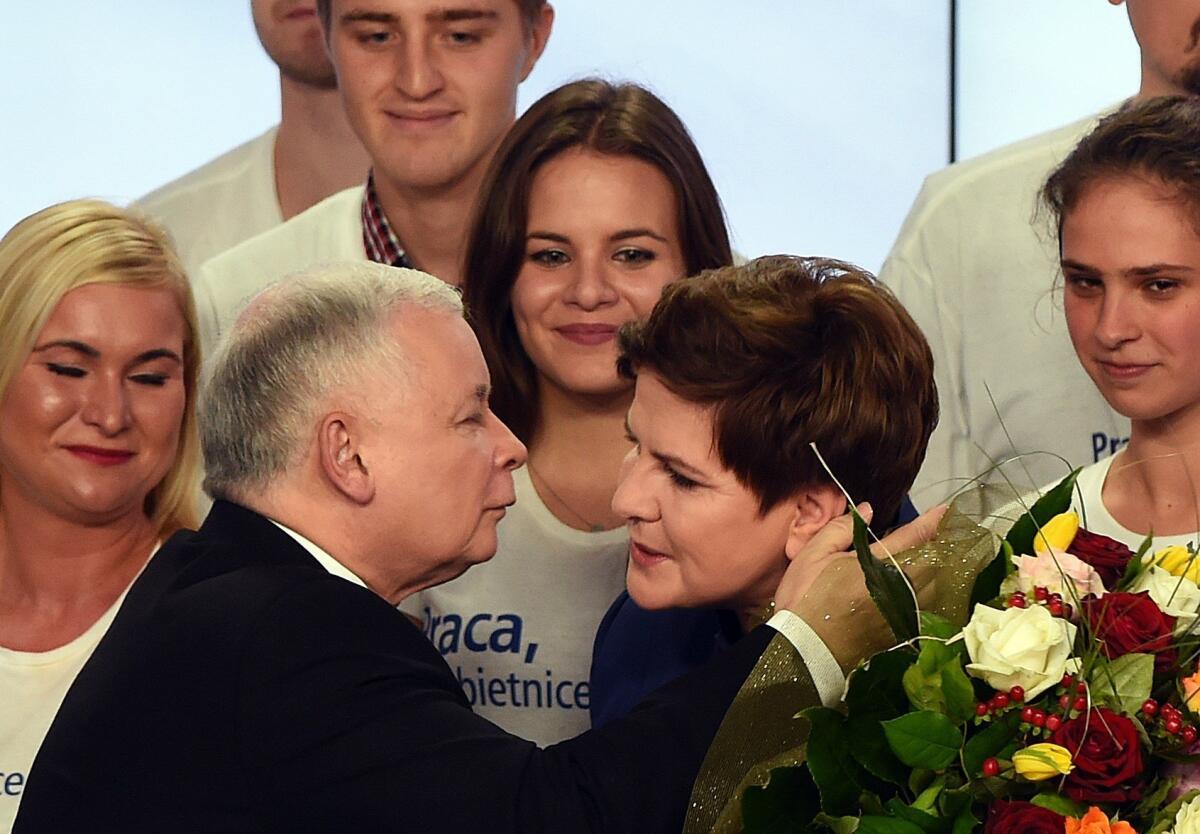 Jaroslaw Kaczynski, left, leader of the conservative opposition Law and Justice party congratulates Beata Szydlo, the party's candidate for prime minister, at the party's headquarters in Warsaw on Sunday.