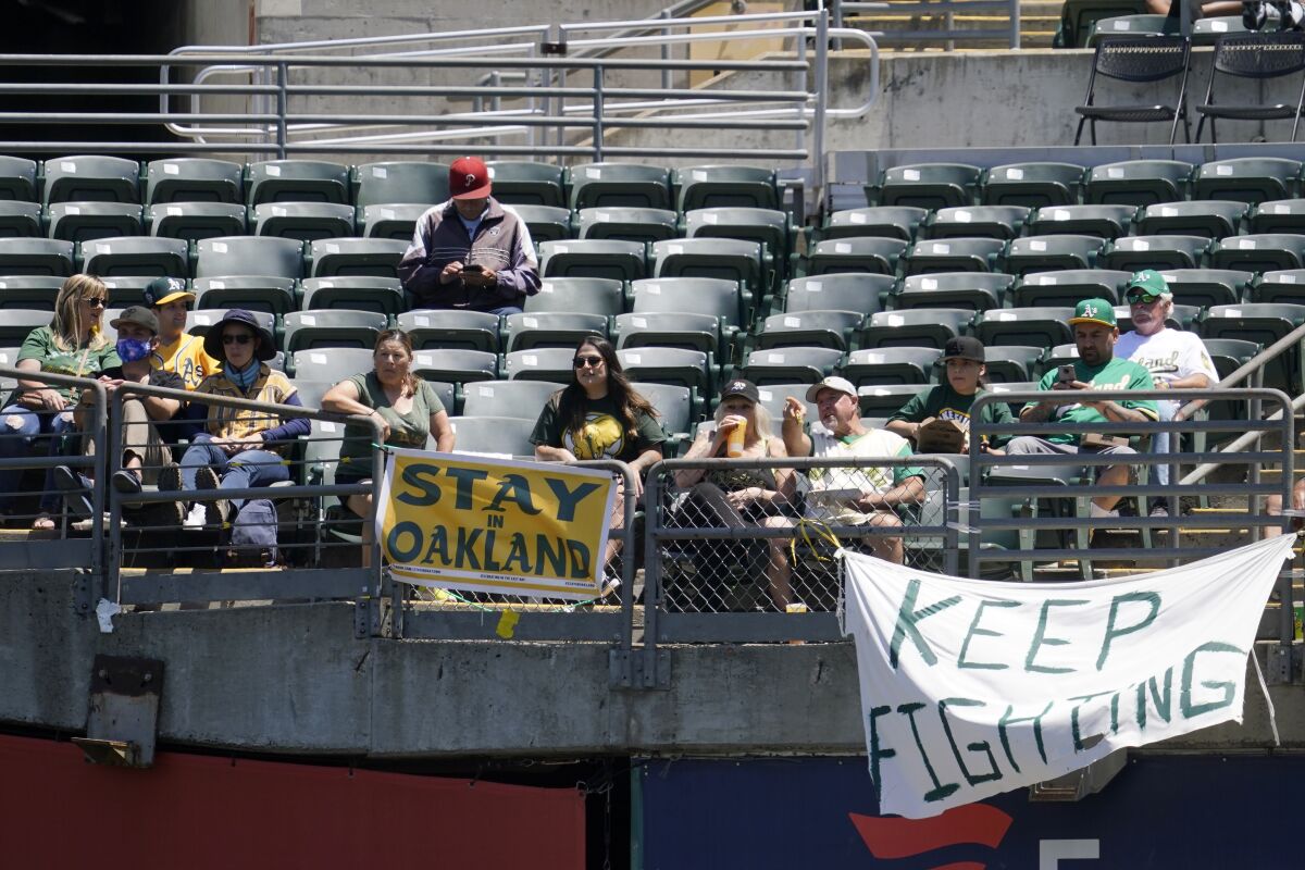 Fans sit behind a sign that reads "Stay in Oakland" during a game between the A's and Angels on July 20, 2021.