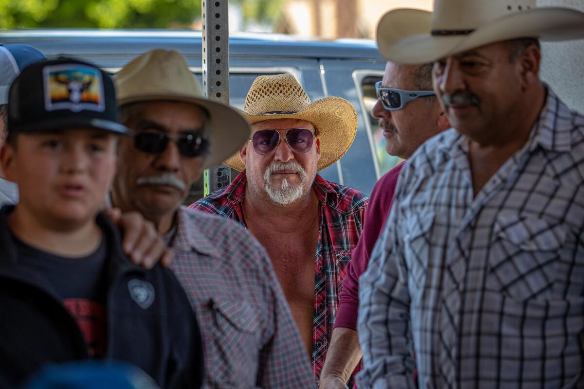 Men in cowboy hats listen to a public meeting.