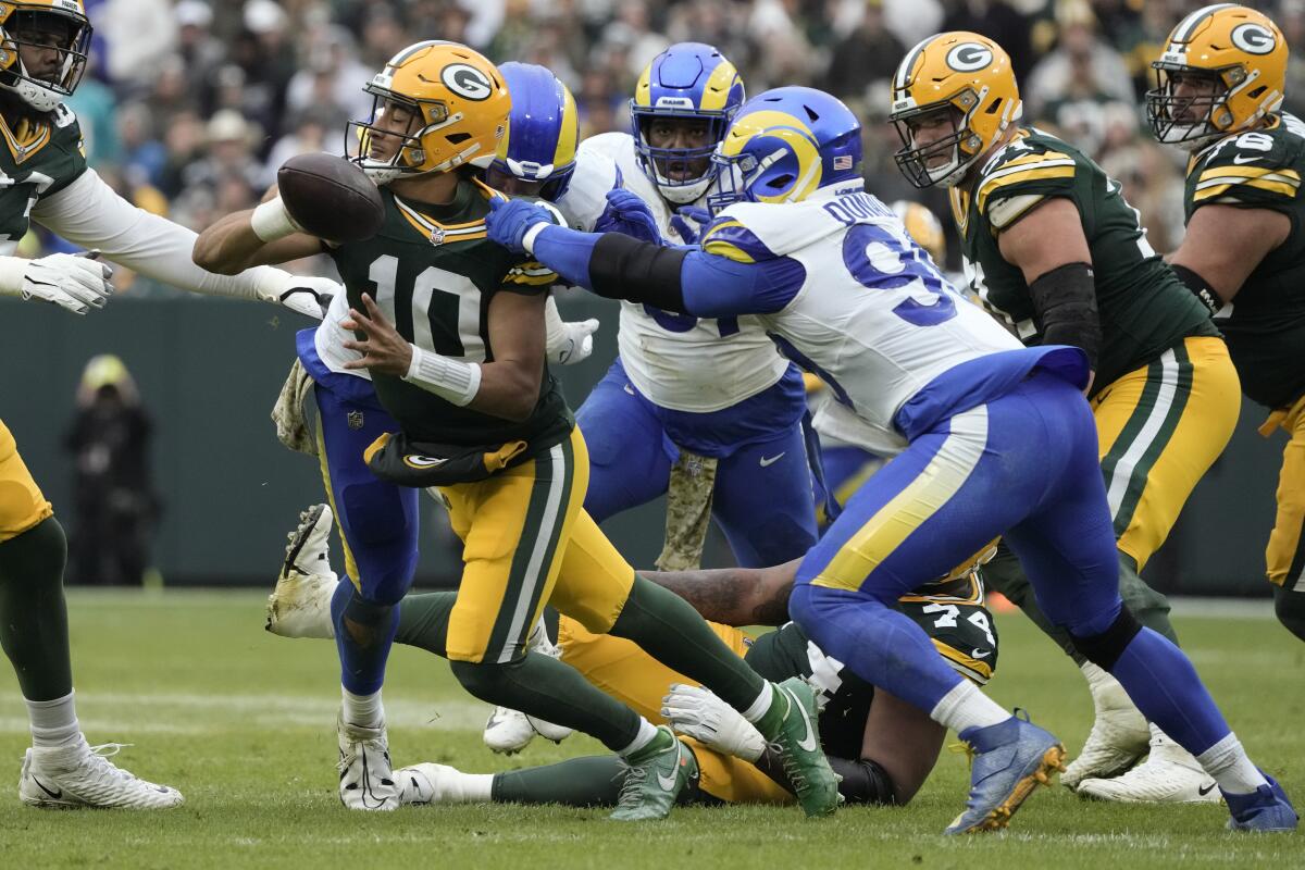 Packers quarterback Jordan Love (10) scrambles as Rams defensive tackle Aaron Donald (99) pursues.