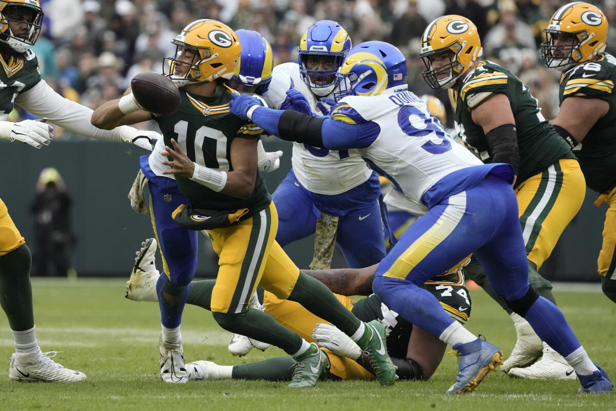 Packers oyun kurucusu Jordan Love (10), Rams'ın defansif mücadelesi Aaron Donald'ın (99) peşinden koşarken mücadele ediyor.