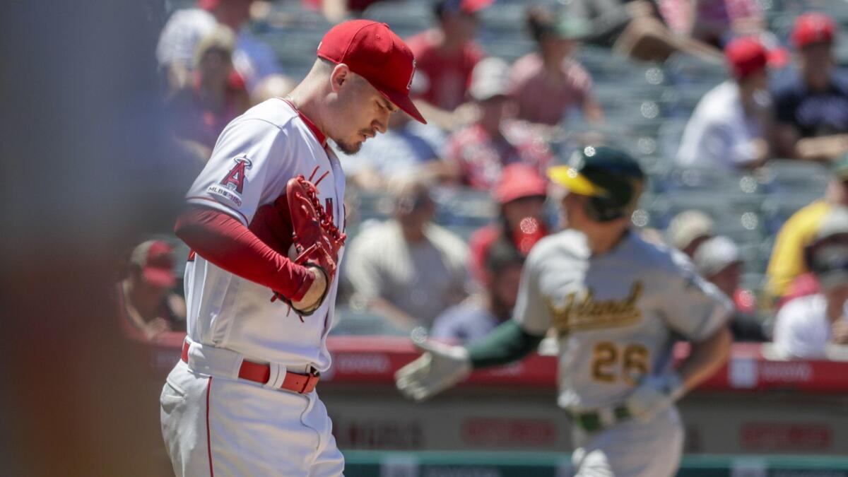 Angels pitcher Andrew Heaney walks back to the mound as Oakland's Matt Chapman rounds the bases after hitting a three-run home run during the fifth inning of the Angels' 12-3 loss Sunday.
