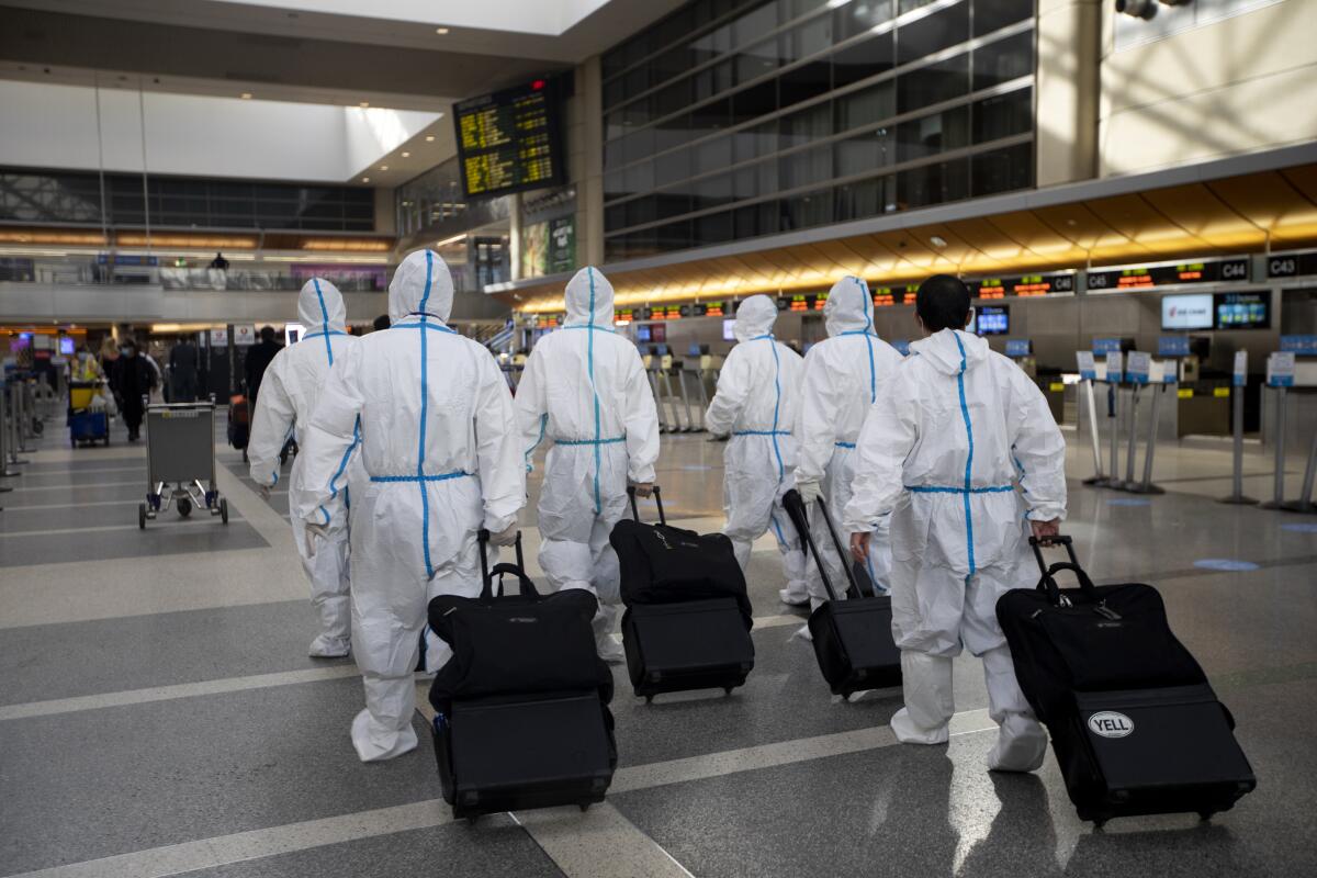 A flight crew wearing personal protective equipment walks through Tom Bradley International Terminal at LAX. 