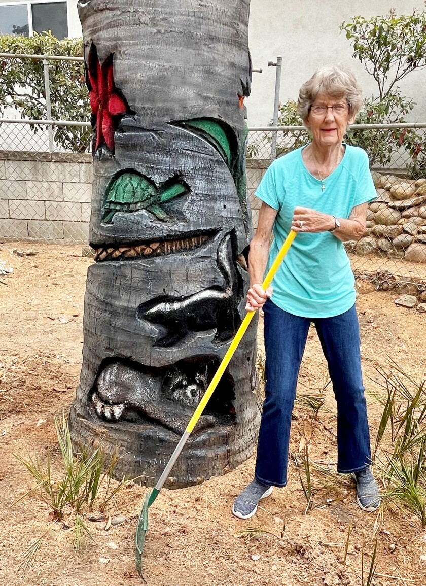 Carol Mulcahy poses with her newly carved palm trunk outside her Pacific Beach home.