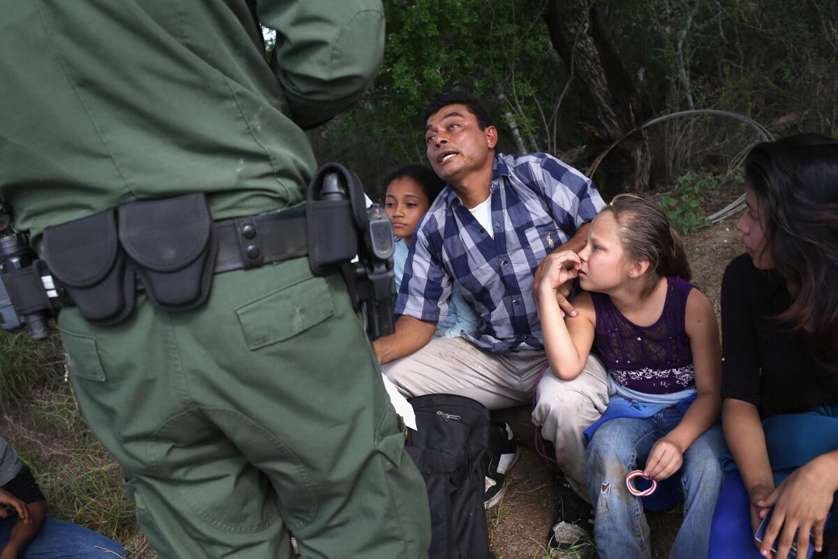 A Border Patrol agent speaks with Central Americans who crossed this week into the United States seeking asylum in Roma, Texas.