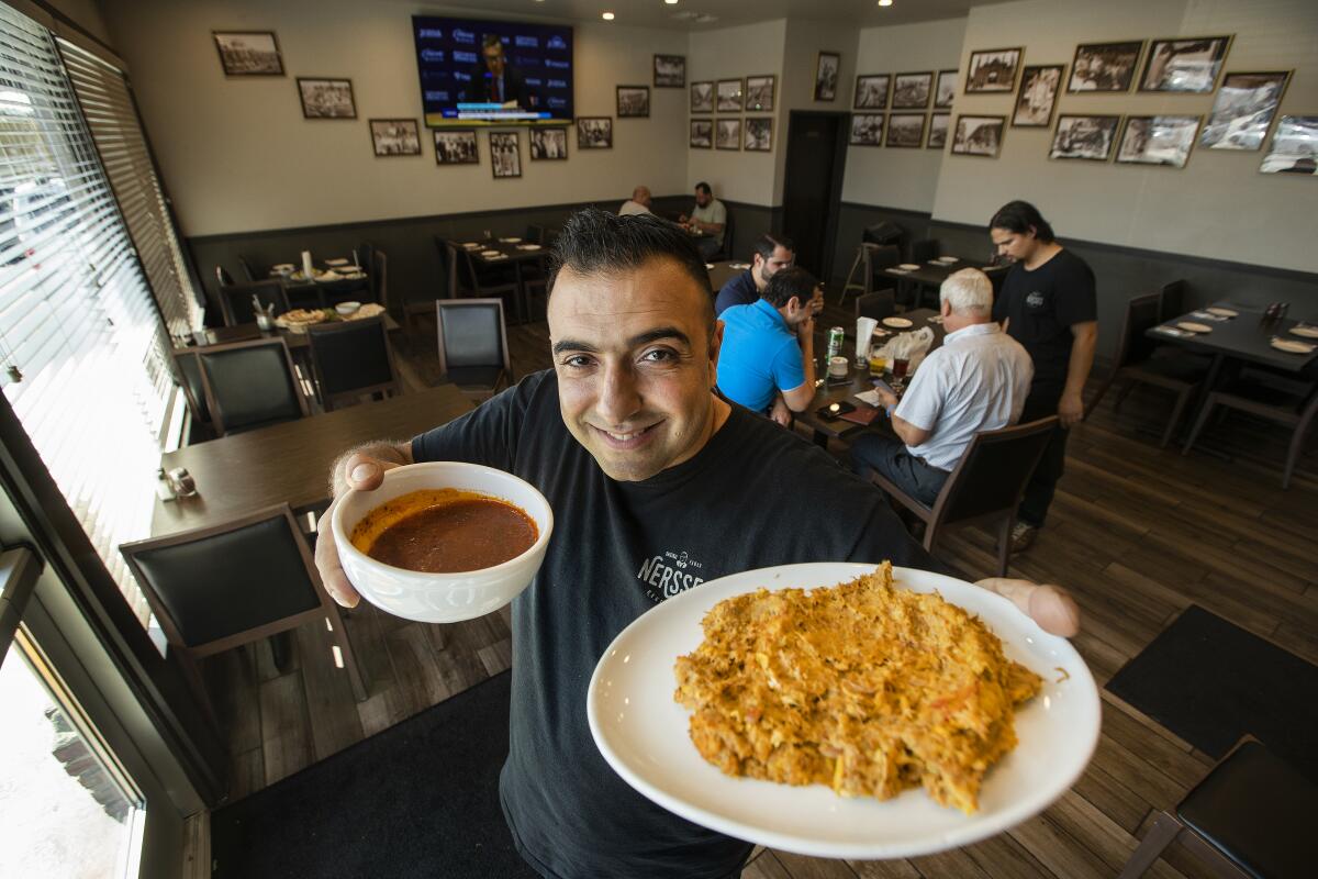 Romik Abediyan, co-owner of Nersses Vanak in Glendale, holds up a plate and a bowl of food