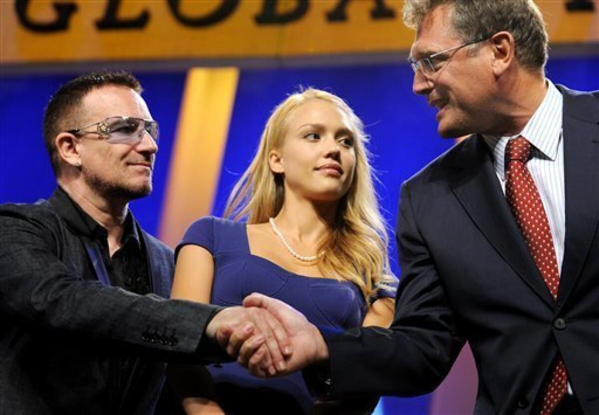 U2's Bono, left, shakes hands with FIFA Secretary General Jerome Valcke, right, as actress Jessica Alba watches during the 2009 Clinton Global Initiative Annual Meeting, Thursday, Sept. 24, 2009 in New York.(AP Photo/Stephen Chernin)