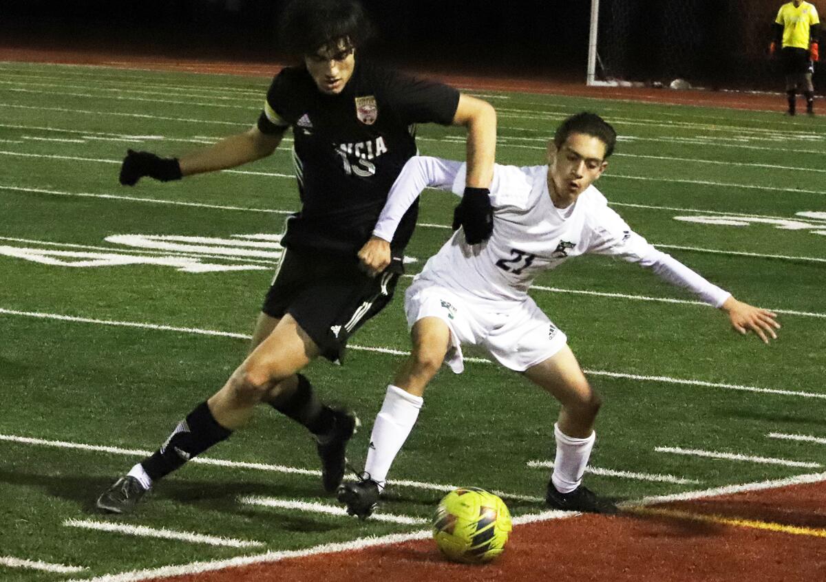 Estancia's Gabe Johner (13) and Costa Mesa's Gio Ortiz (21) compete for the ball in the Battle for the Bell on Friday.