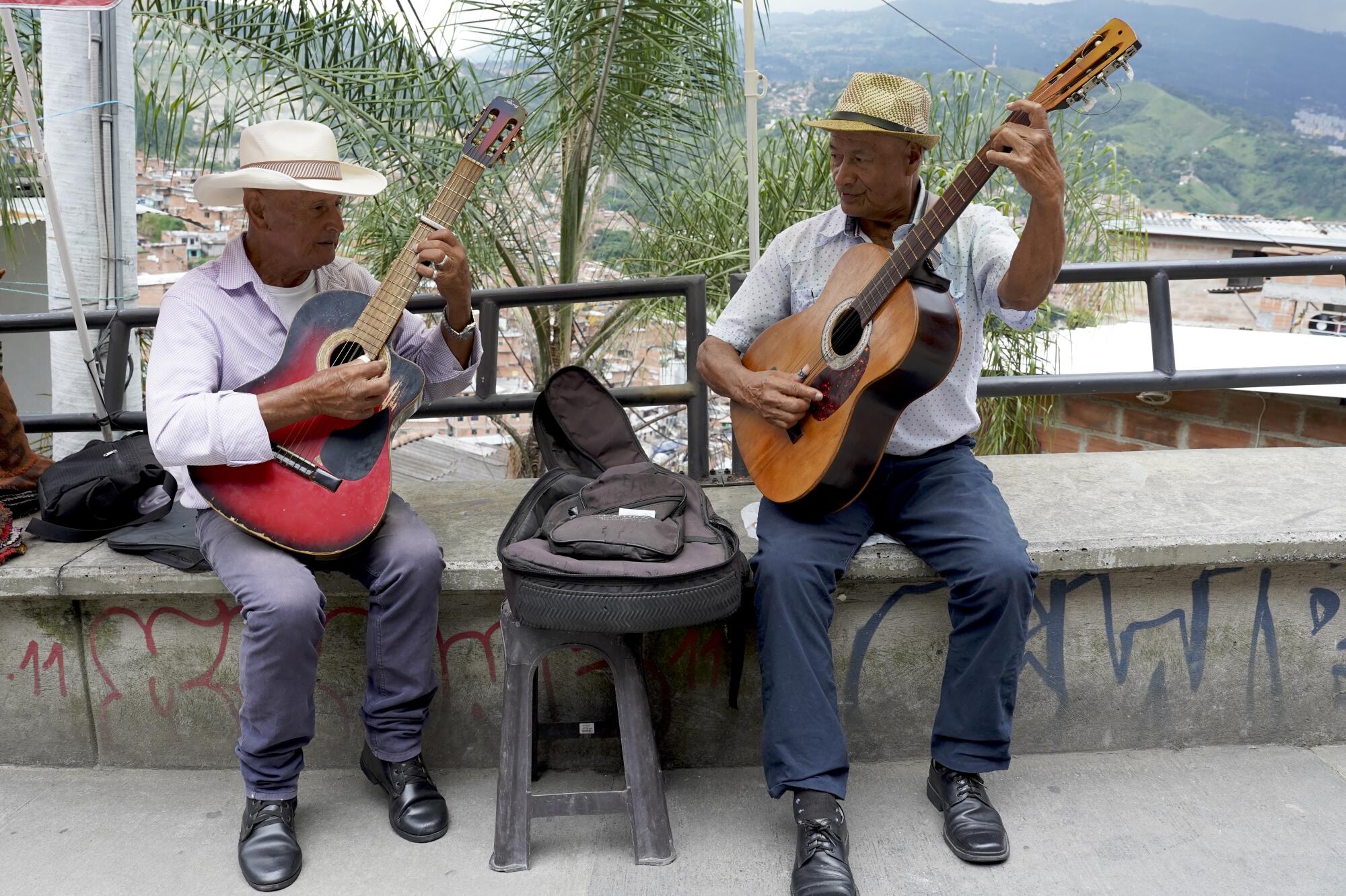Two men wearing hats play their guitars.