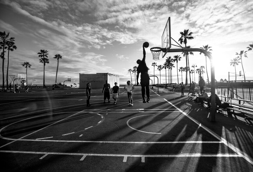 A basketball player leaps up to make a shot while other players look on