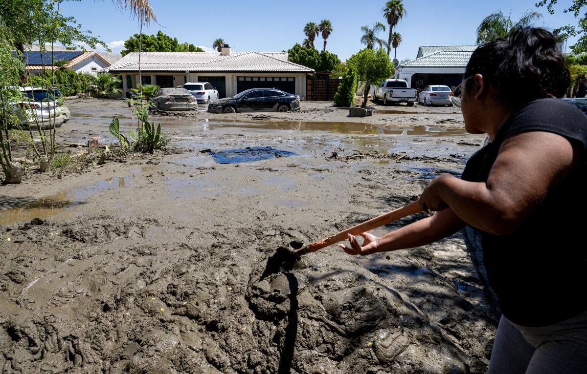 Rebecca Garnica shovels mud out of her driveway