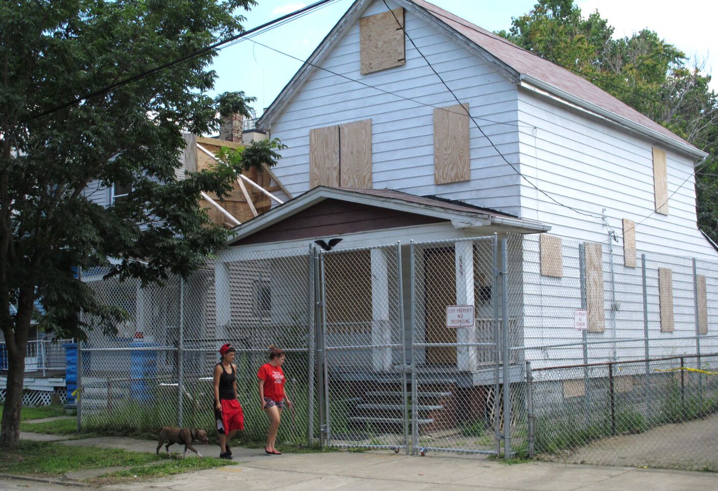 Neighbors Jessica Rodriguez and Caitlin Coyne, both 19, walk last month past the house where Ariel Castro kept three women captive for a decade. The house was torn down Wednesday.