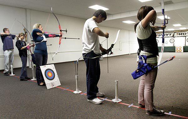 Archers practice shooting at Hi-Tech Archery in Fullerton. Ranges that used to attract just a handful of hobbyists are now crowded with would-be Katnisses and Robin Hoods. Requests for archery lessons for birthday parties have increased.